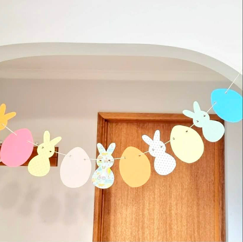 Colorful Easter banner with bunnies and eggs hanging above a wooden door.