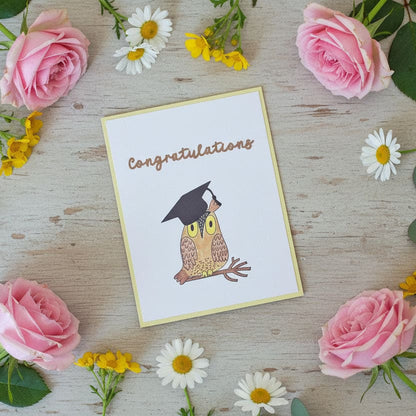 Greeting card with an owl wearing a graduation cap on a wooden surface