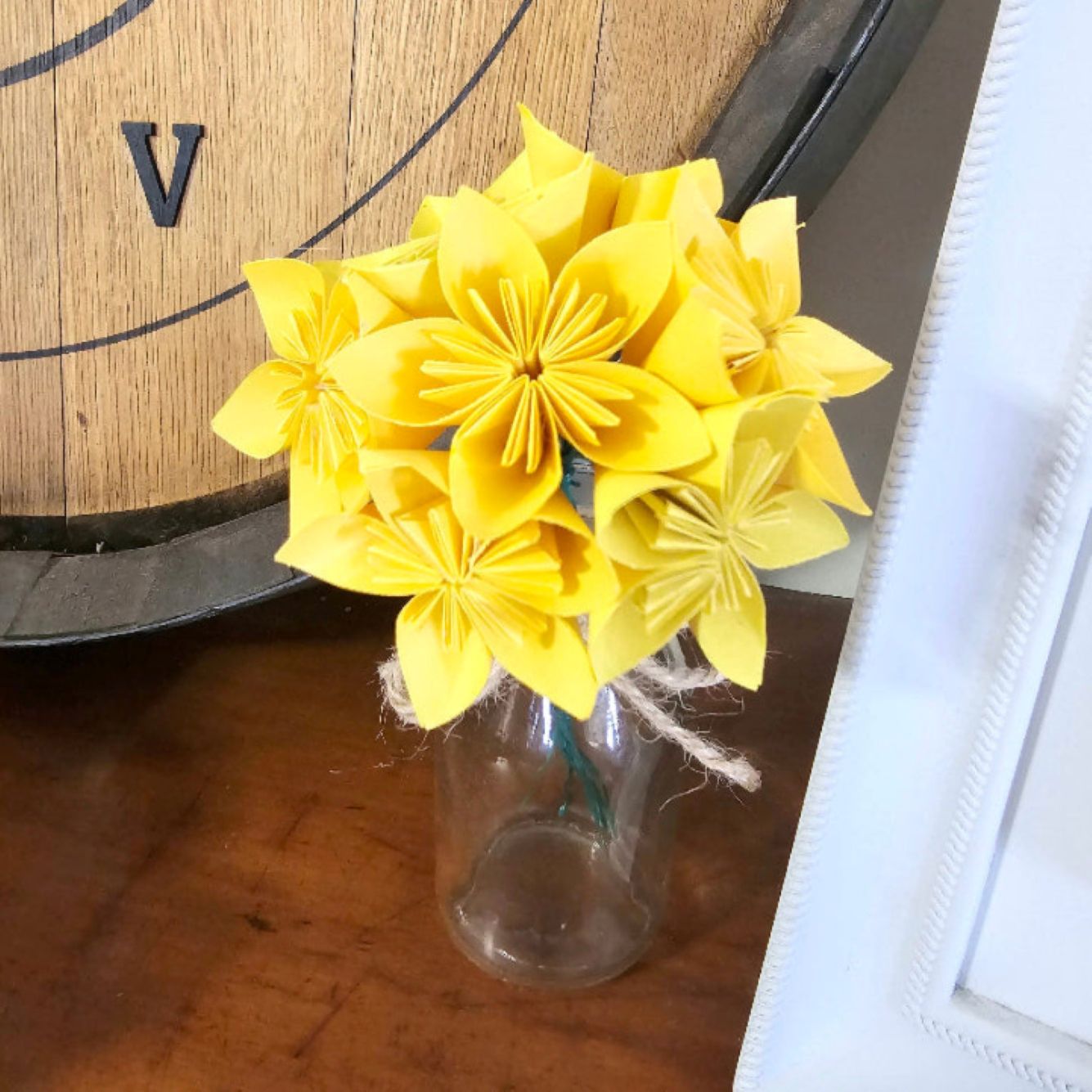 Yellow flowers in a clear glass bottle on a wooden surface